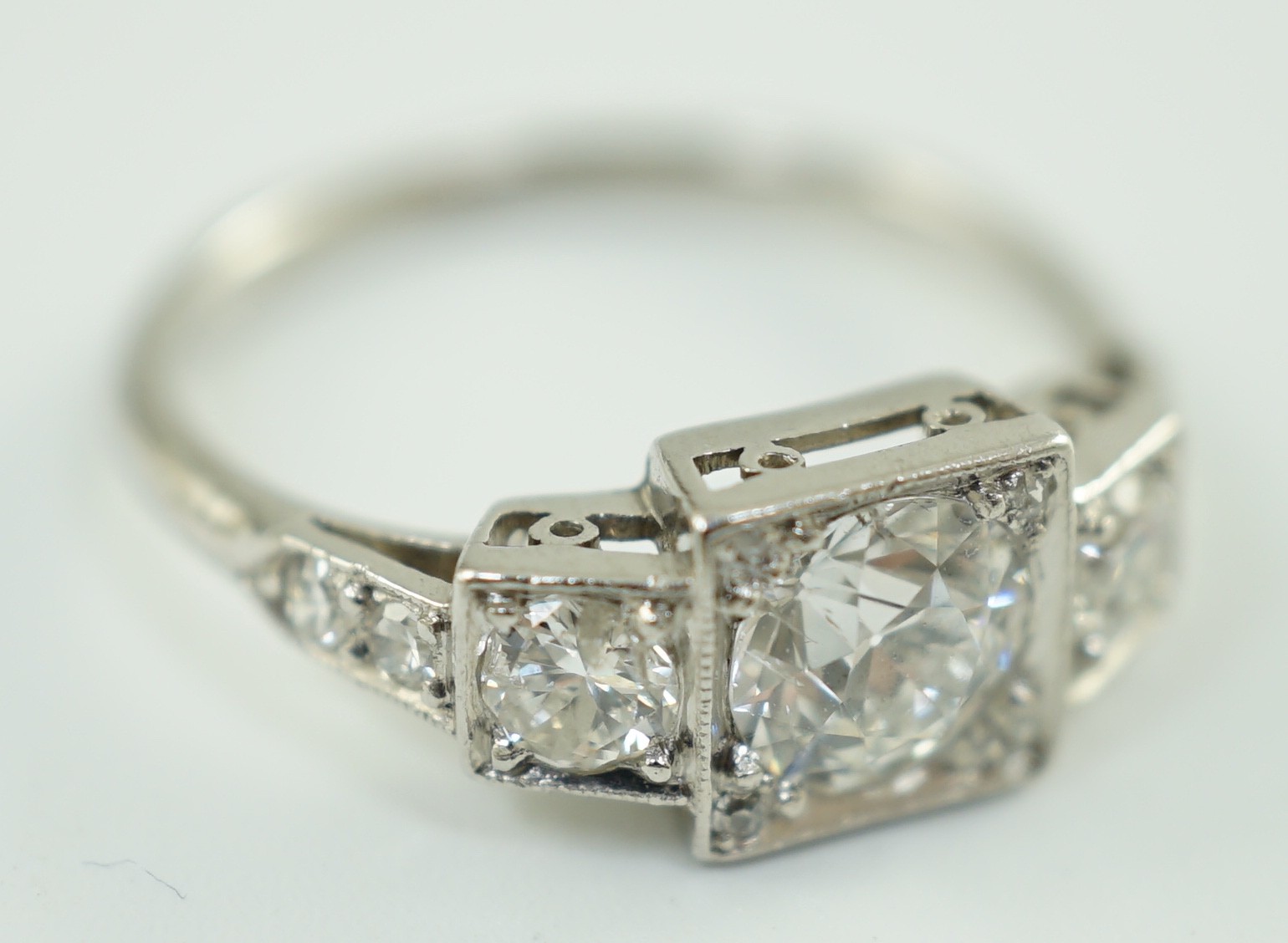 A platinum and millegrain set three stone diamond ring, with diamond set shoulders